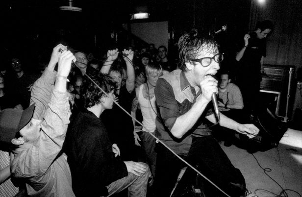 Frodus performing live, singer at the microphone with the crowd's arms raised
